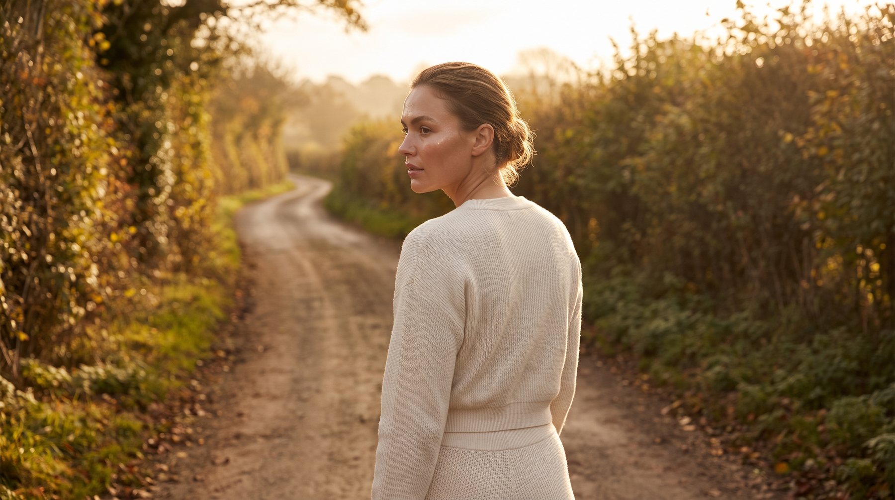A woman walking a quiet country lane in low golden light